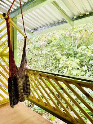 a hammock hanging on a porch with a window at Cascada Verde Eco Lodge & Hostel in Uvita