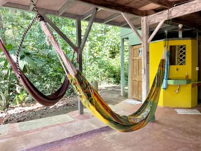 a hammock hanging from a porch of a house at Cascada Verde Eco Lodge & Hostel in Uvita