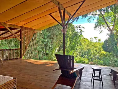 a wooden deck with a chair and an umbrella at Cascada Verde Eco Lodge & Hostel in Uvita
