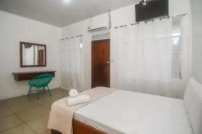 a bedroom with a bed and a chair and a mirror at Puntarenas Bed & Coffee by Aldea in Puntarenas