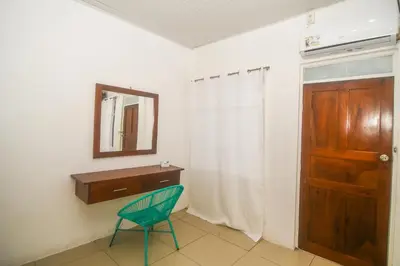 a room with a chair and a mirror and a door at Puntarenas Bed & Coffee by Aldea in Puntarenas