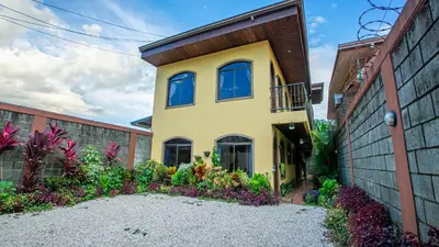 a yellow house with blue windows and plants at Sol y Luna Apartments in Fortuna
