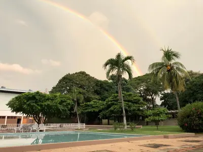 a rainbow over a swimming pool with palm trees at Hotel Diriá Santa Cruz in Santa Cruz