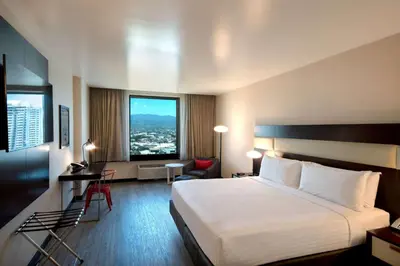 a hotel room with a bed and a large window at D Sabana Hotel San José in San José