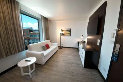 a living room with a white couch and a tv at D Sabana Hotel San José in San José