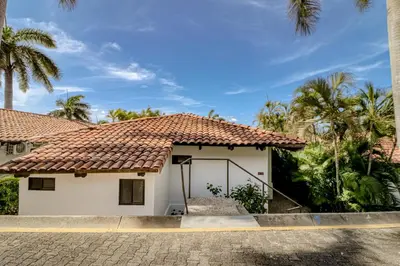 a house with a tile roof and palm trees at Villa Sol 35 in Playa Hermosa