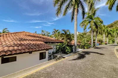 a house with a tiled roof and palm trees at Villa Sol 35 in Playa Hermosa