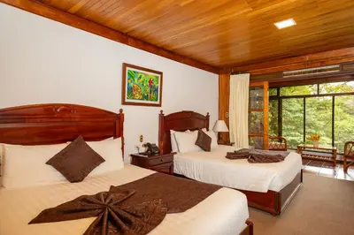 a bedroom with two beds and a large window at Trapp Family Lodge Monteverde in Monteverde Costa Rica