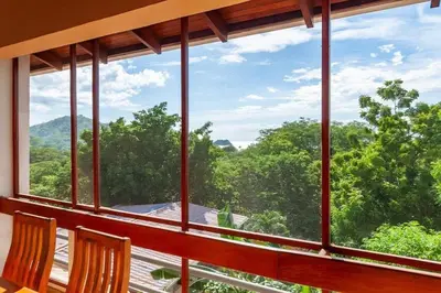 a room with a large window with a view of trees at Tropical Condo with Spectacular Ocean Views, Panoramic Dining Terrace & Quick Walk to Beach in Coco