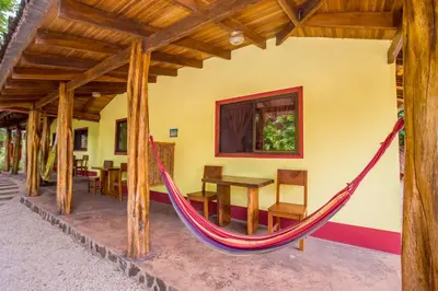 a hammock in a house with a table and chairs at Indra Inn in Playa Grande