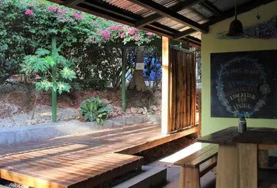a wooden porch with a bench and a sign on it at Indra Inn in Playa Grande