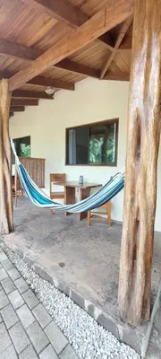 a hammock in a room with a table and a tv at Indra Inn in Playa Grande