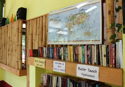 a book shelf with books and a map of the world at Indra Inn in Playa Grande