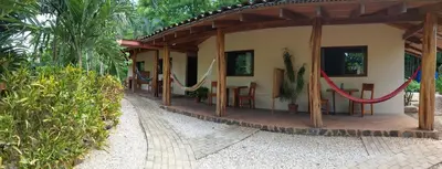 a house with a porch with hammocks on it at Indra Inn in Playa Grande