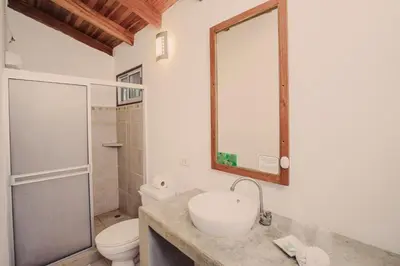 a bathroom with a sink and a toilet and a mirror at Indra Inn in Playa Grande