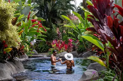 two people in the water in a pool in a garden at Hotel Arenal Kioro Suites & Spa in Fortuna