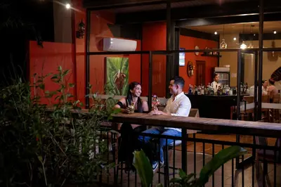 a man and woman sitting at a table in a restaurant at Hotel Arenal Kioro Suites & Spa in Fortuna