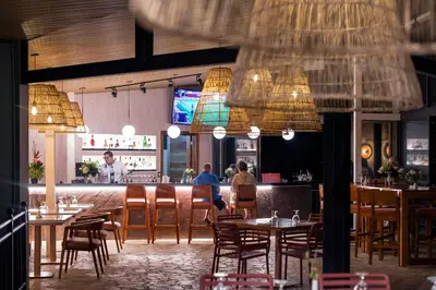 a restaurant with tables and chairs and a bar at Hotel Arenal Kioro Suites & Spa in Fortuna