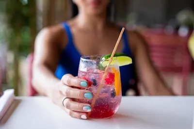 a woman sitting at a table holding a drink at Hotel Arenal Kioro Suites & Spa in Fortuna