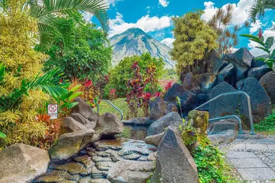 a garden with a mountain in the background at Hotel Arenal Kioro Suites & Spa in Fortuna