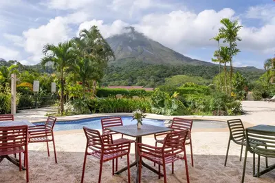 a table and chairs with a mountain in the background at Hotel Arenal Kioro Suites & Spa in Fortuna