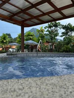 a swimming pool with an umbrella and anophe at Hotel Villas Vilma in Fortuna