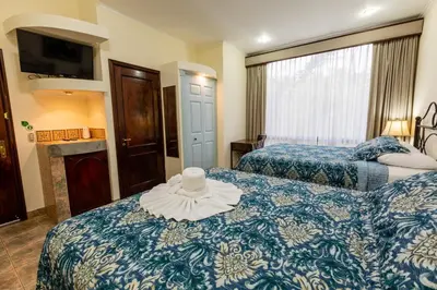 a hotel room with two beds and a hat on the bed at Casas del Toro in Monteverde Costa Rica
