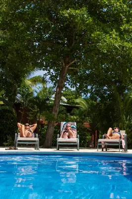 two people sitting in lawn chairs next to a pool at Boutique Surf Hotel Rip Jack Inn in Playa Grande