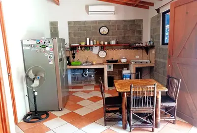 a kitchen with a table and a refrigerator at Domi Cabin in Dominical