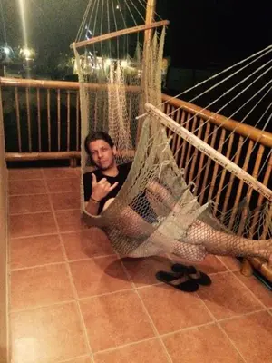 a man sitting in a hammock on a porch at Domi Cabin in Dominical