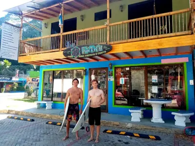 two men standing in front of a building holding their surfboards at Domi Cabin in Dominical