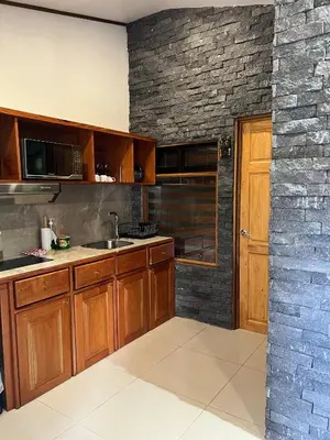 a kitchen with wooden cabinets and a brick wall at Apartamento Don Jarvey II in Monteverde Costa Rica