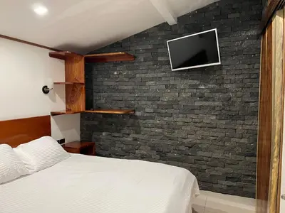 a bedroom with a bed and a tv on a brick wall at Apartamento Don Jarvey II in Monteverde Costa Rica