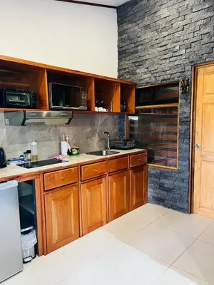 a kitchen with wooden cabinets and a brick wall at Apartamento Don Jarvey II in Monteverde Costa Rica