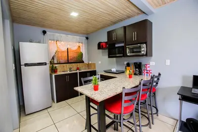 a kitchen with a table with chairs and a refrigerator at Casa Suculenta ,Monteverde con Jacuzzi Privado y Lavandería in Monteverde Costa Rica