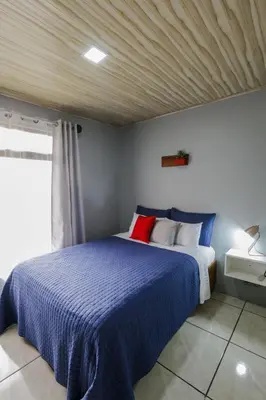 a bedroom with a bed with a blue comforter at Casa Suculenta ,Monteverde con Jacuzzi Privado y Lavandería in Monteverde Costa Rica