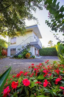 a house with red flowers in front of it at Casa Suculenta ,Monteverde con Jacuzzi Privado y Lavandería in Monteverde Costa Rica