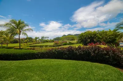a park with palm trees and green grass and flowers at Del Mar 4N 3 bdr Garden View in Los Suenos in Herradura