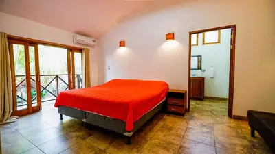 a bedroom with a bed with a red bedspread at Casa tropical - Fabulous tropical house in Tamarindo