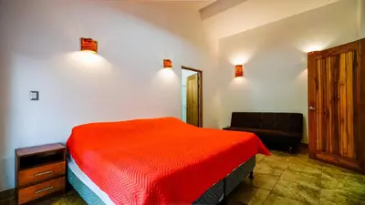 a bedroom with a red bed and a couch at Casa tropical - Fabulous tropical house in Tamarindo