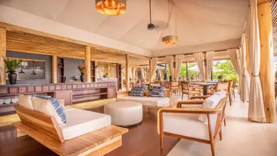 an open living room with wooden furniture and windows at Nayara Tented Camp in Fortuna