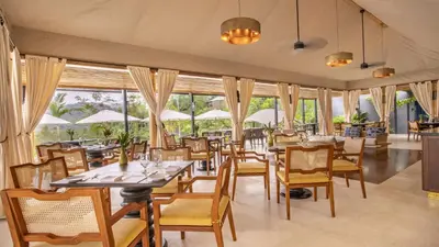a restaurant with tables and chairs and windows at Nayara Tented Camp in Fortuna