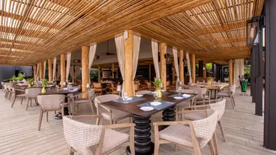 a restaurant with tables and chairs and a wooden ceiling at Nayara Tented Camp in Fortuna