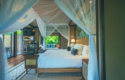 a bedroom with a large bed with blue drapes at Nayara Tented Camp in Fortuna