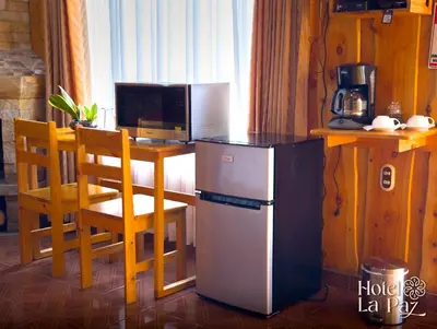 a kitchen with a small refrigerator and a table with a microwave at Hotel La Paz in Poasito