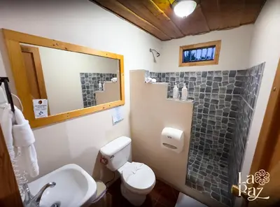 a bathroom with a toilet and a sink and a mirror at Hotel La Paz in Poasito