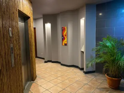a hallway with a plant and a painting on the wall at Alajuela Backpackers Airport Hostel in Alajuela City
