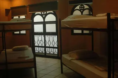 a room with three bunk beds and a window at Alajuela Backpackers Airport Hostel in Alajuela City