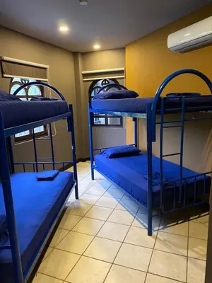 a room with three bunk beds with blue sheets at Alajuela Backpackers Airport Hostel in Alajuela City