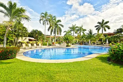 a swimming pool in a resort with palm trees at Bay Residence 7C 3 bdr Ocean View in Los Suenos in Herradura